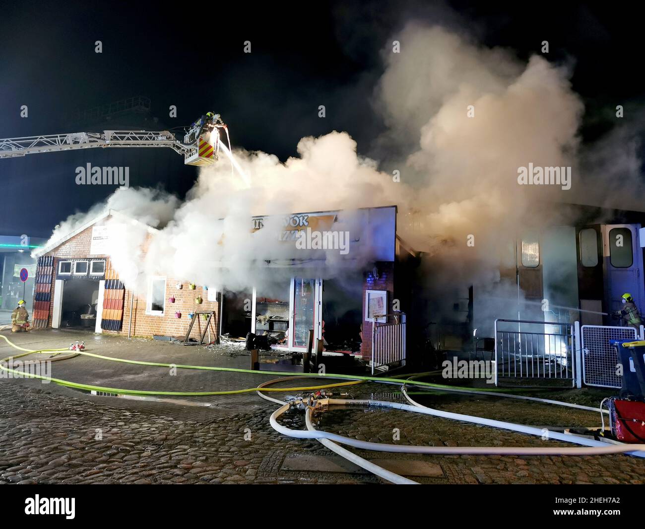 11. Januar 2022, Schleswig-Holstein, Mölln: Feuerwehrleute versuchen, einen Brand auf einem Gebäude zu löschen. Aus noch unbekannten Gründen ist auf einem alten Hafengelände in Mölln (Herzogtum Lauenburg) ein Großbrand ausgebrochen. Ein Lieferrestaurant, ein Dachunternehmen und ein angrenzendes Lagerhaus wurden durch die Flammen beschädigt, sagte eine Polizeisprecherin am Dienstagmorgen. Foto: --/TNN/dpa Stockfoto