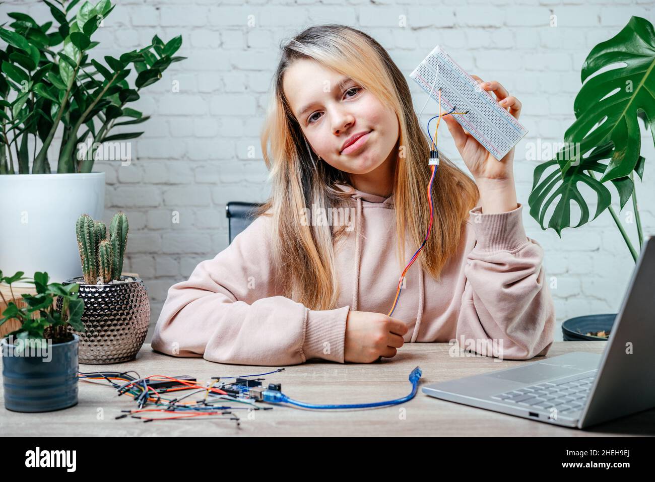 Ein Teenager-Mädchen mit einem Sensorchip, das zu Hause Robotik, MINT- und arduino-Codierungskurse für Kinder studiert Stockfoto