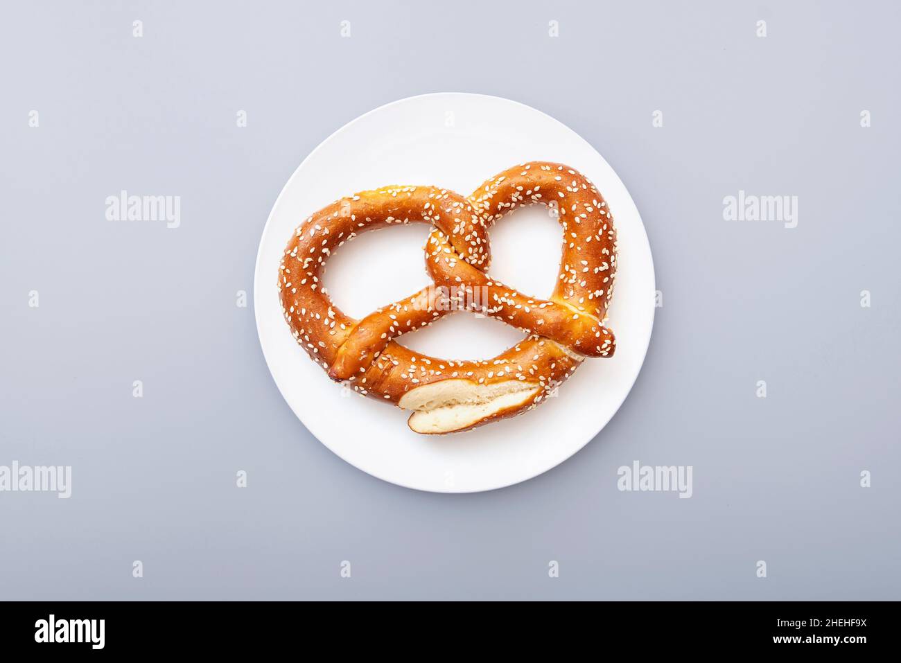 Brezel als Oktoberfest-Symbol auf weißer Keramikplatte, Draufsicht Stockfoto