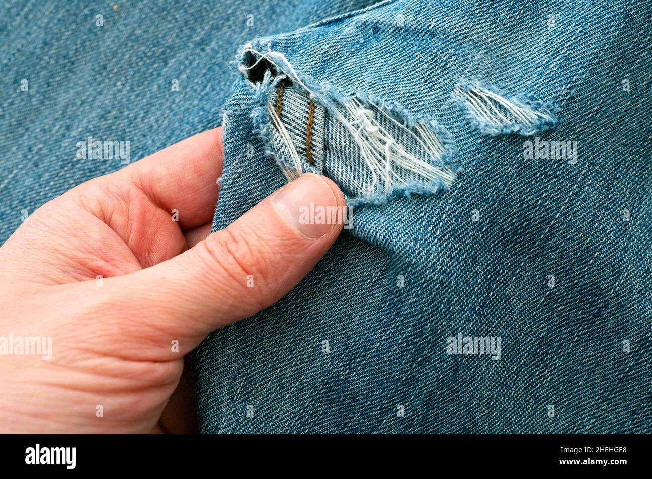 Mann erkunden Loch in zerrissene Jeans, bevor sie nähen Stockfoto