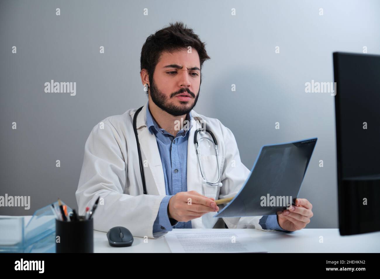 Der junge Arzt schaute erstaunt auf die Röntgenaufnahme eines Beckens und einer Wirbelsäule. Stockfoto