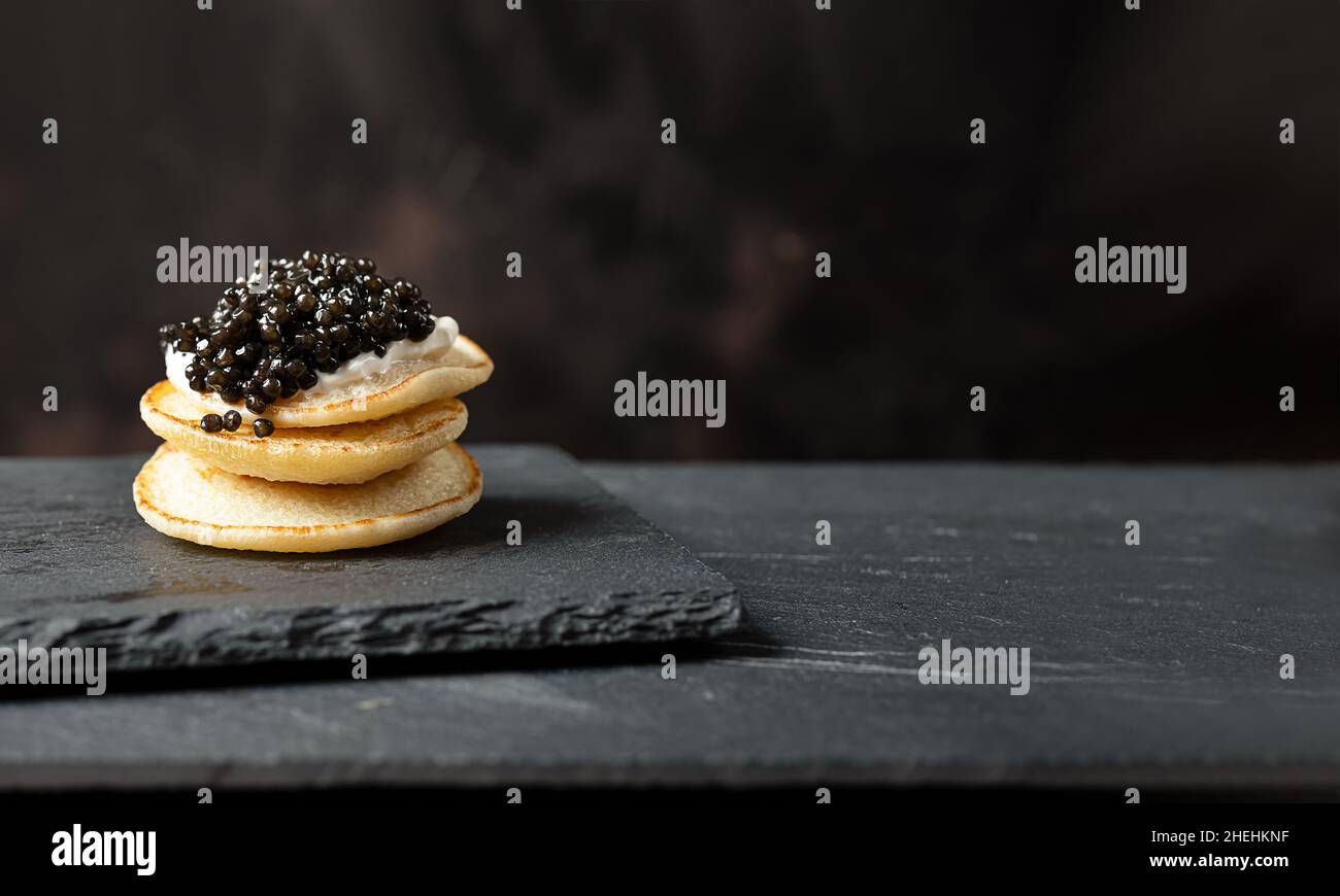 Ein Stapel Blini-Pfannkuchen mit schwarzem Kaviar und saurer Creme auf einem Schiefer, kopieren Platz Stockfoto