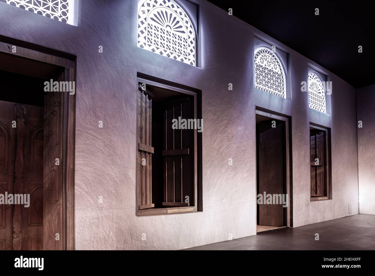 Fensterportale im arabischen Stil und geschnitzte Holztüren mit Arabesken-Ornamenten, traditionelle arabische Architektur mit moderner Beleuchtung, Dubai, VAE. Stockfoto
