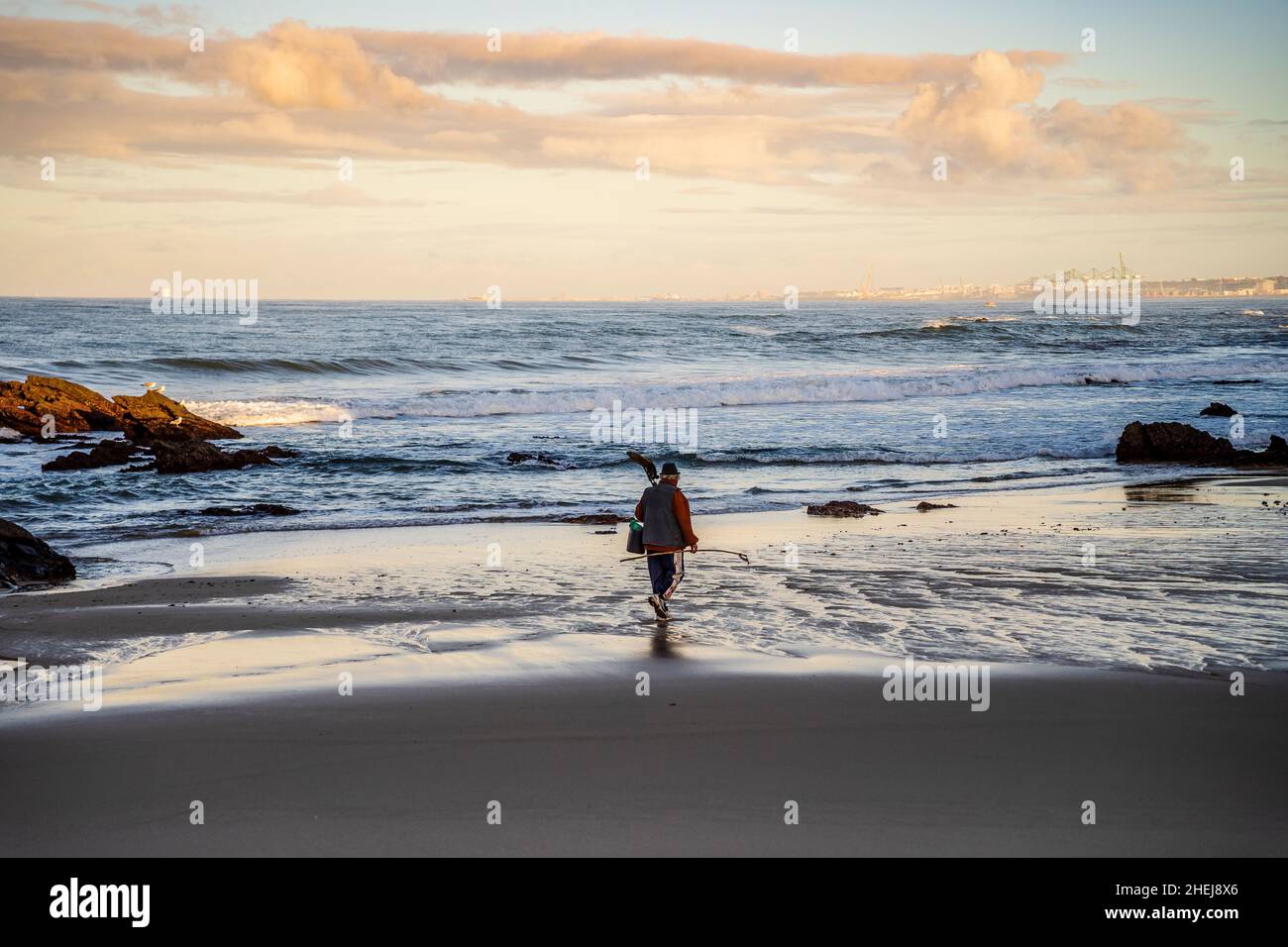 Ein Fischer, der am Strand von Samoqueira zwischen Sines und Porto Covo, Alentejo, Portugal, spazieren geht Stockfoto