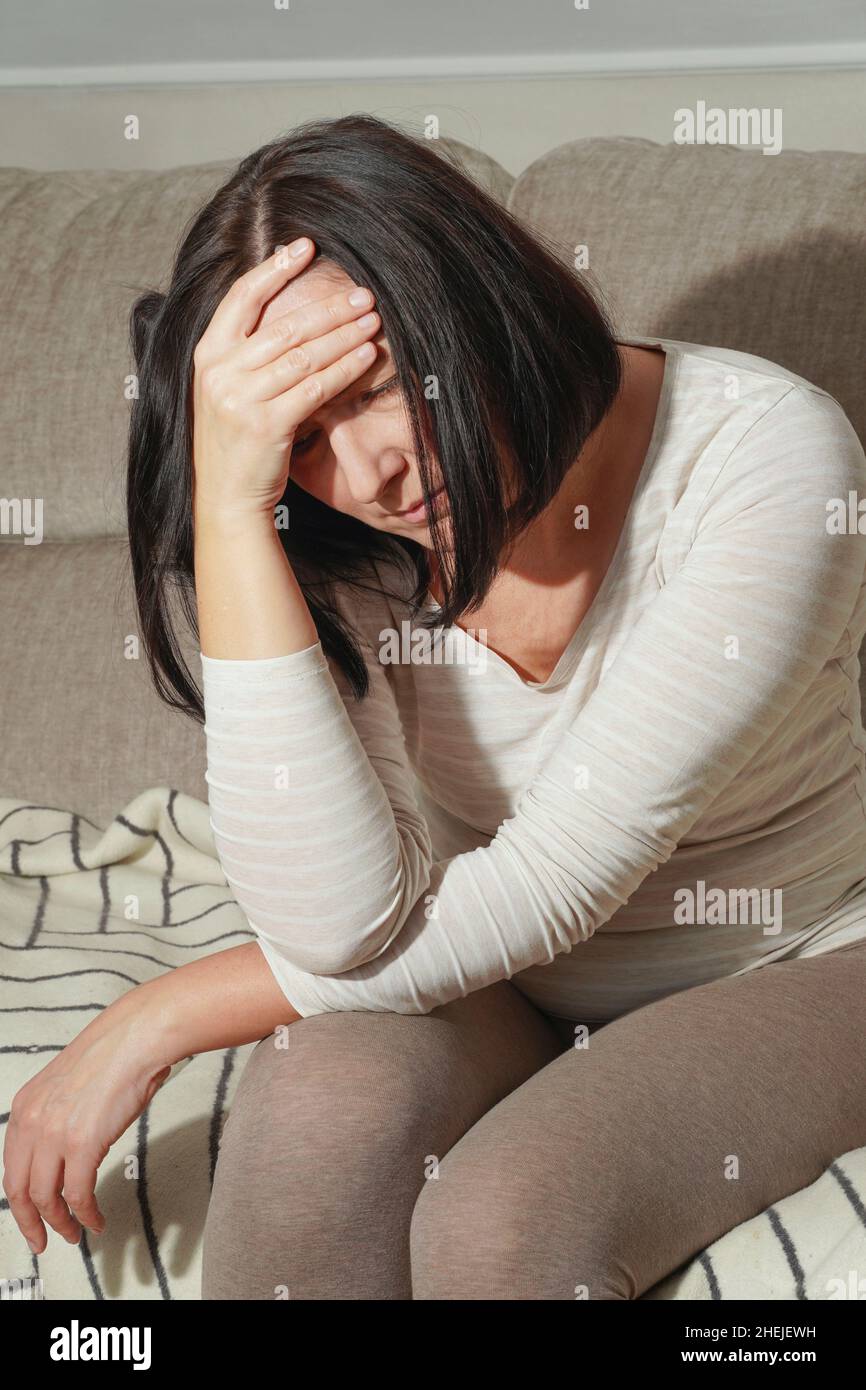 Ältere Frau mittleren Alters mit Kopfschmerzen, Migräne oder Depressionen. Frau in Schmerzen, traurig, müde, gestresst. Konzept der Trauer. Stockfoto