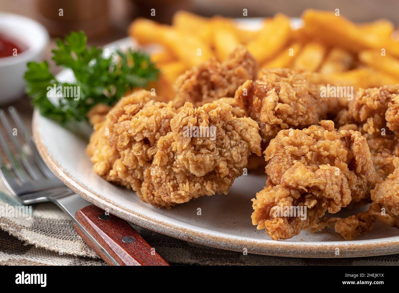 Knusprig gebratene Hähnchengerichte und pommes frites mit Petersilie auf einem Teller garniert Stockfoto