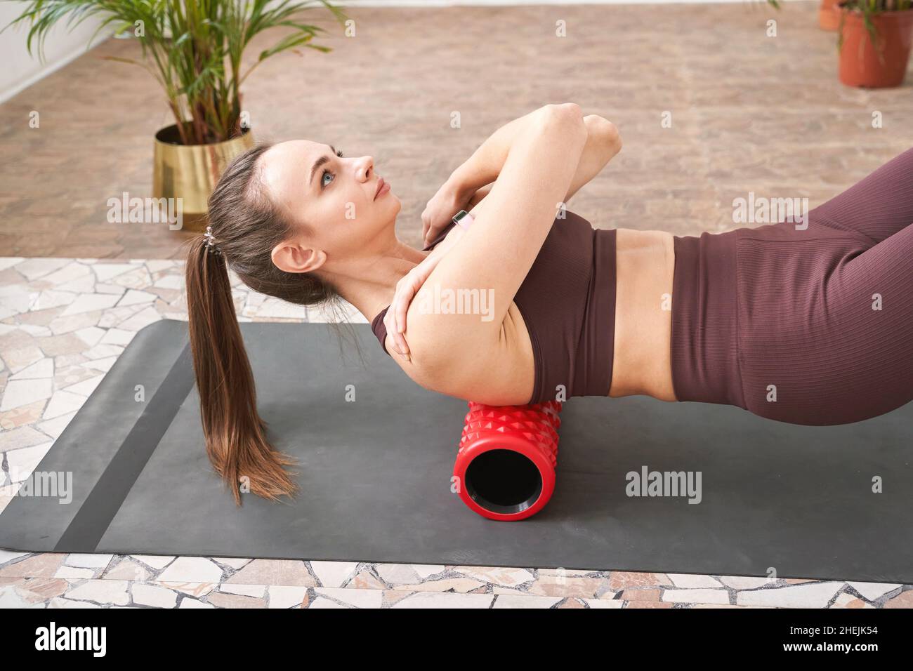 Junge Frau dehnt den Körper auf einer Fitnessmatte. Myofasziale Freisetzungsmassage Stockfoto