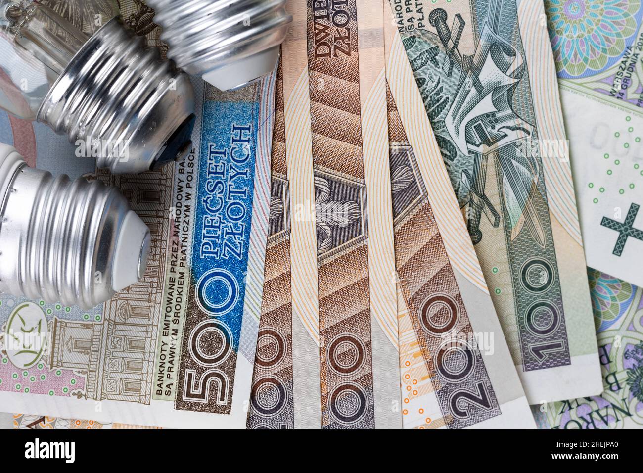 LED-Lampen und viele polnische Banknoten. Anstieg der Strompreise in Polen. Foto aufgenommen unter künstlichem, weichem Licht Stockfoto