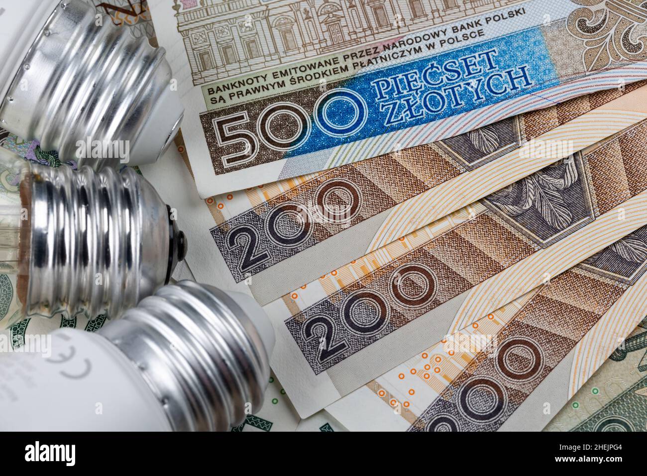 LED-Lampen und viele polnische Banknoten. Anstieg der Strompreise in Polen. Foto aufgenommen unter künstlichem, weichem Licht Stockfoto