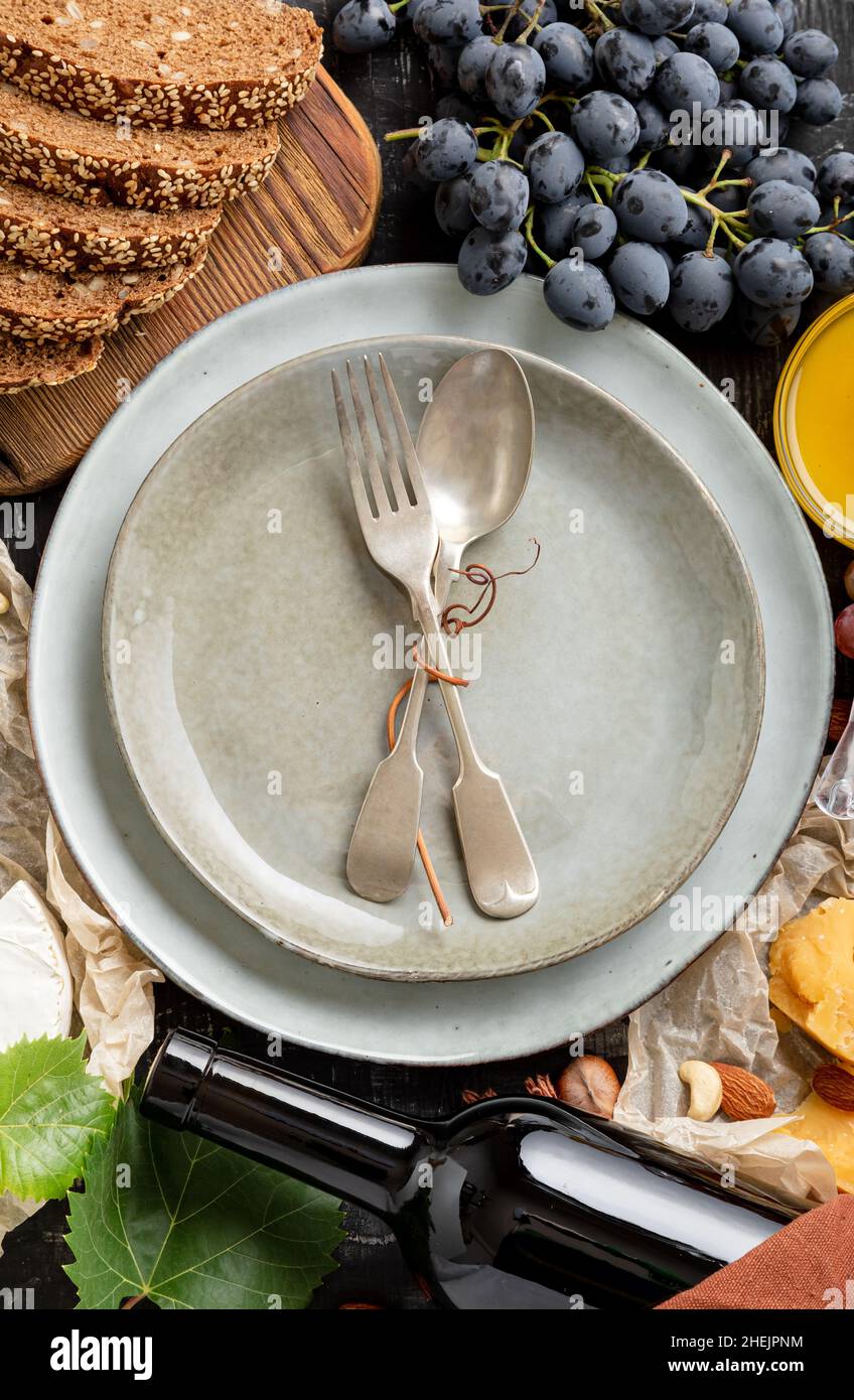 Leere Portion grauen Teller mit Gabel Löffel im Rahmen von Lebensmitteln Lebensmittelzutaten mediterrane Küche. Blaue Teller in Rahmen von Lebensmitteln, Wein, Käse Stockfoto