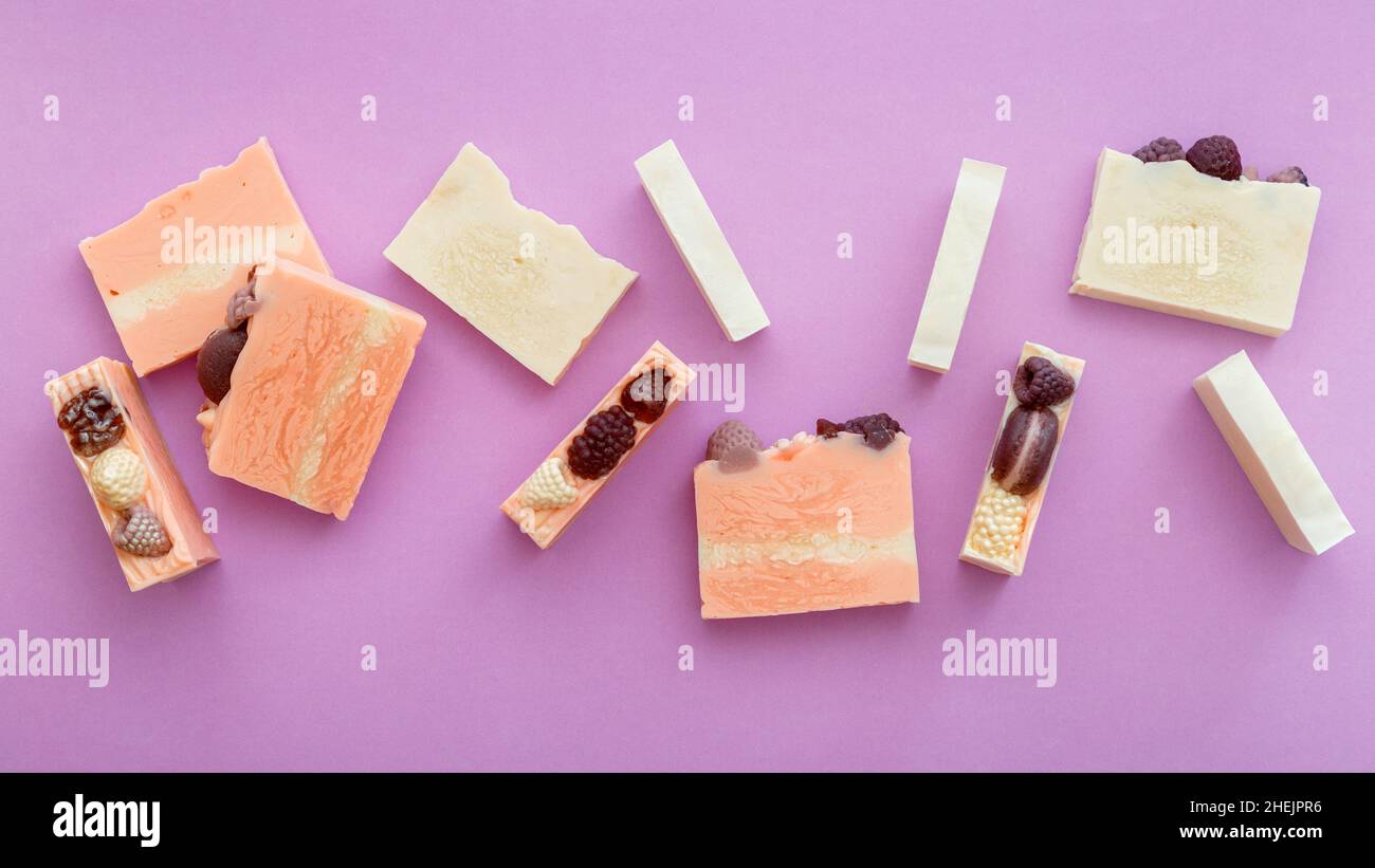 Natürliche handgemachte Seifenstücke flach Lay Zusammensetzung. Viele duftende handgemachte Spa Bio rosa weiße Seifenstücke. Hausgemachte Beauty-Produkte auf lila Stockfoto