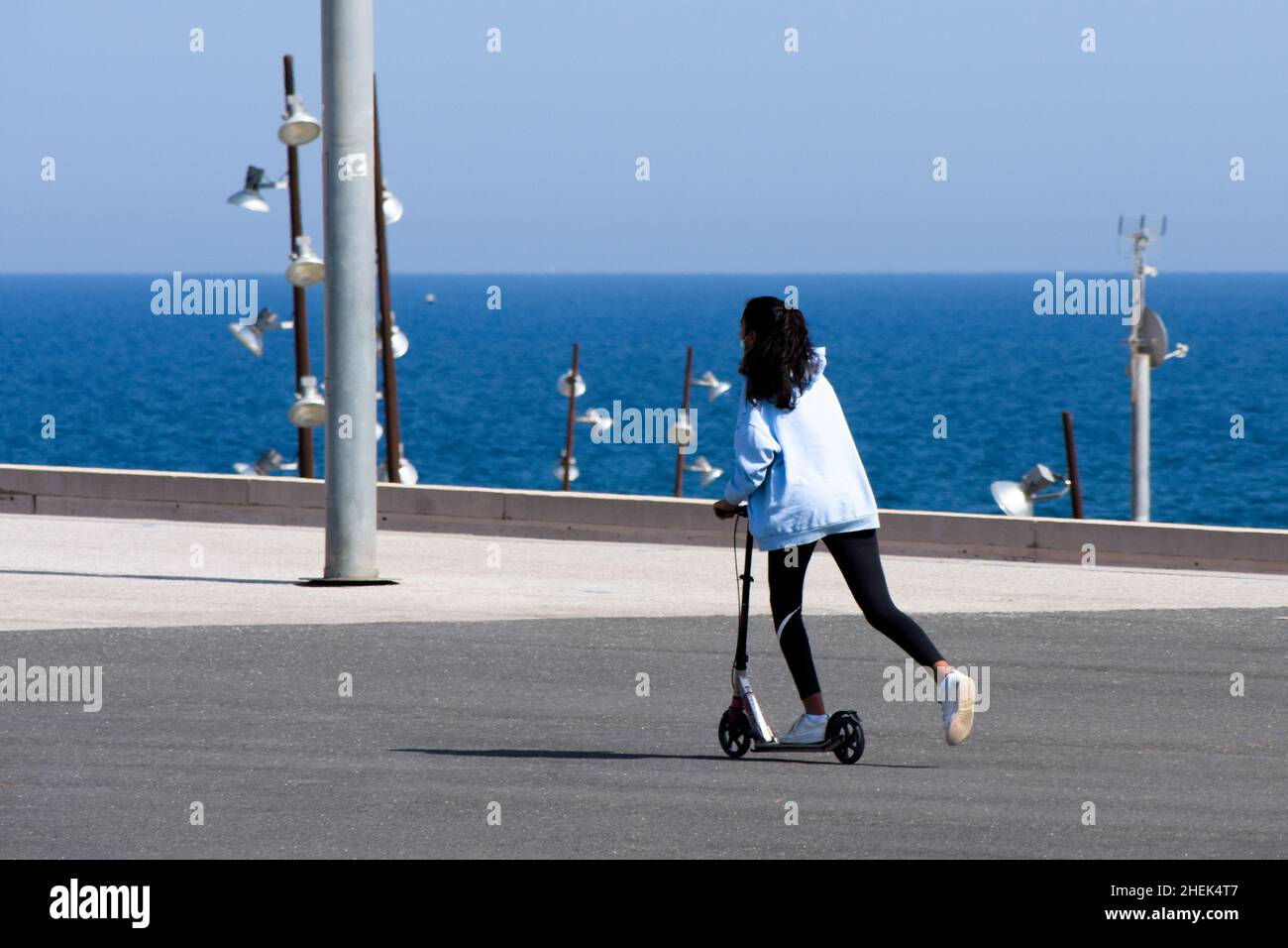 Teenager Mädchen Reiten auf Roller in einer Promenade. Stockfoto