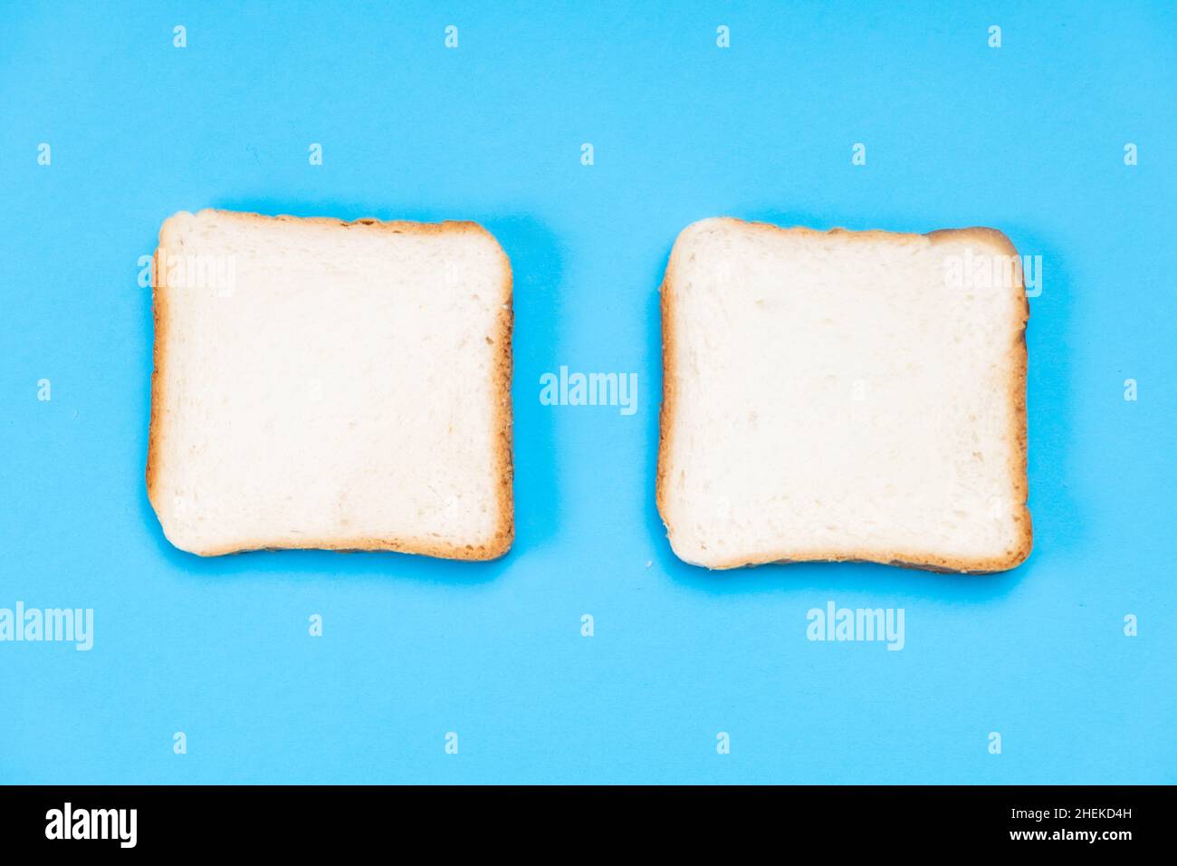 Zwei weiße Toaststücke auf blauem Hintergrund. Lebensmittelkonzept. Stockfoto