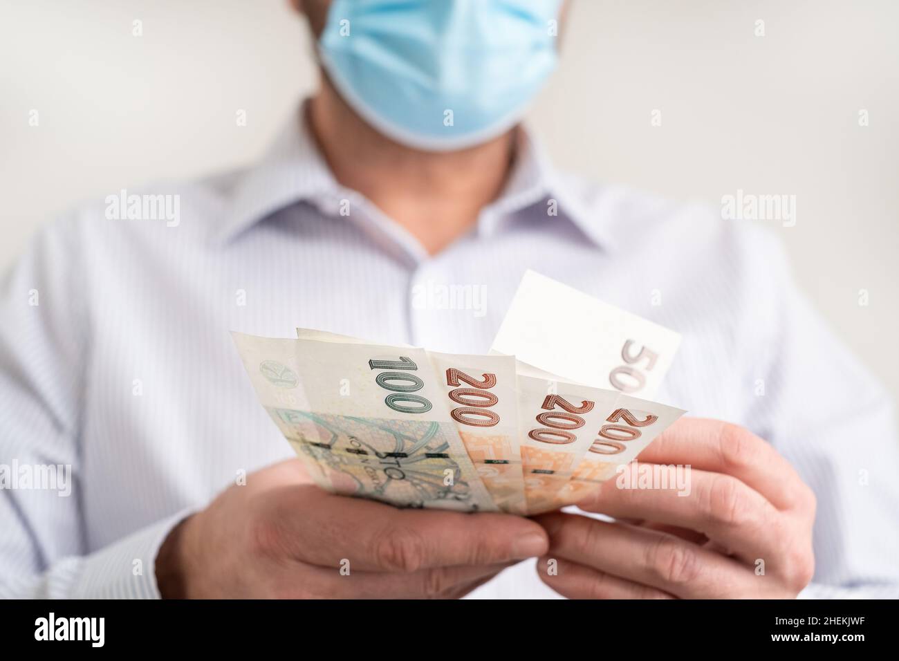 Zählen kleine Geldscheine der Tschechischen Republik Koruna. Finanzierung während des Coronavirus in Tschechien Konzept. CZK kleine Banknoten. Mann in einer schützenden Medica Stockfoto