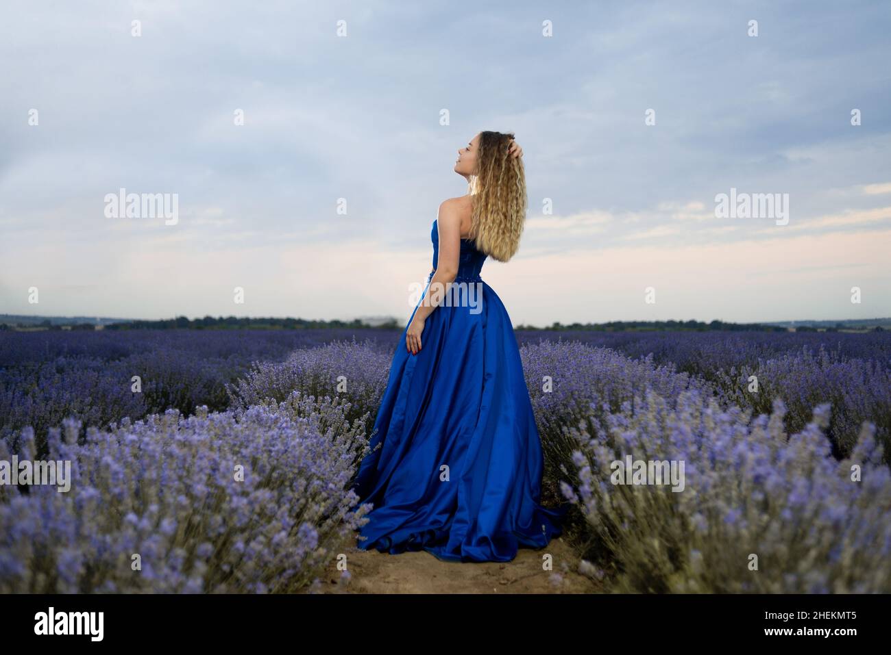 Mädchen Tourist in einem langen blauen Kleid auf einem Lavendelfeld zwischen blühenden duftenden Blumen. Natur und Aromatherapie im Sommer. Weibliches Model in einem langen Kleid Stockfoto