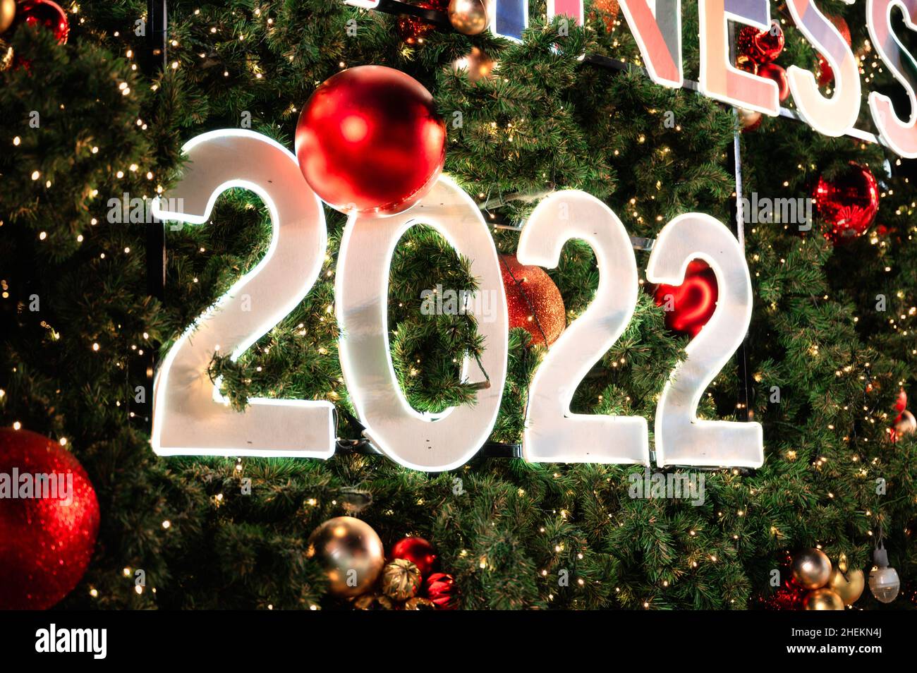 Frohes neues Jahr 2022 glühend auf weihnachtsbaum und Ornament Kugeln in Weihnachtsfest Stockfoto