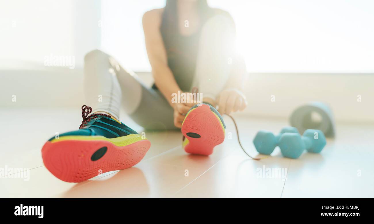 Fitness zu Hause immer in Form für Silvester Auflösung. Frau schnürten Laufschuhe für das Indoor-Workout Cardio-Bodentraining auf einer Yogamatte. Banner Stockfoto