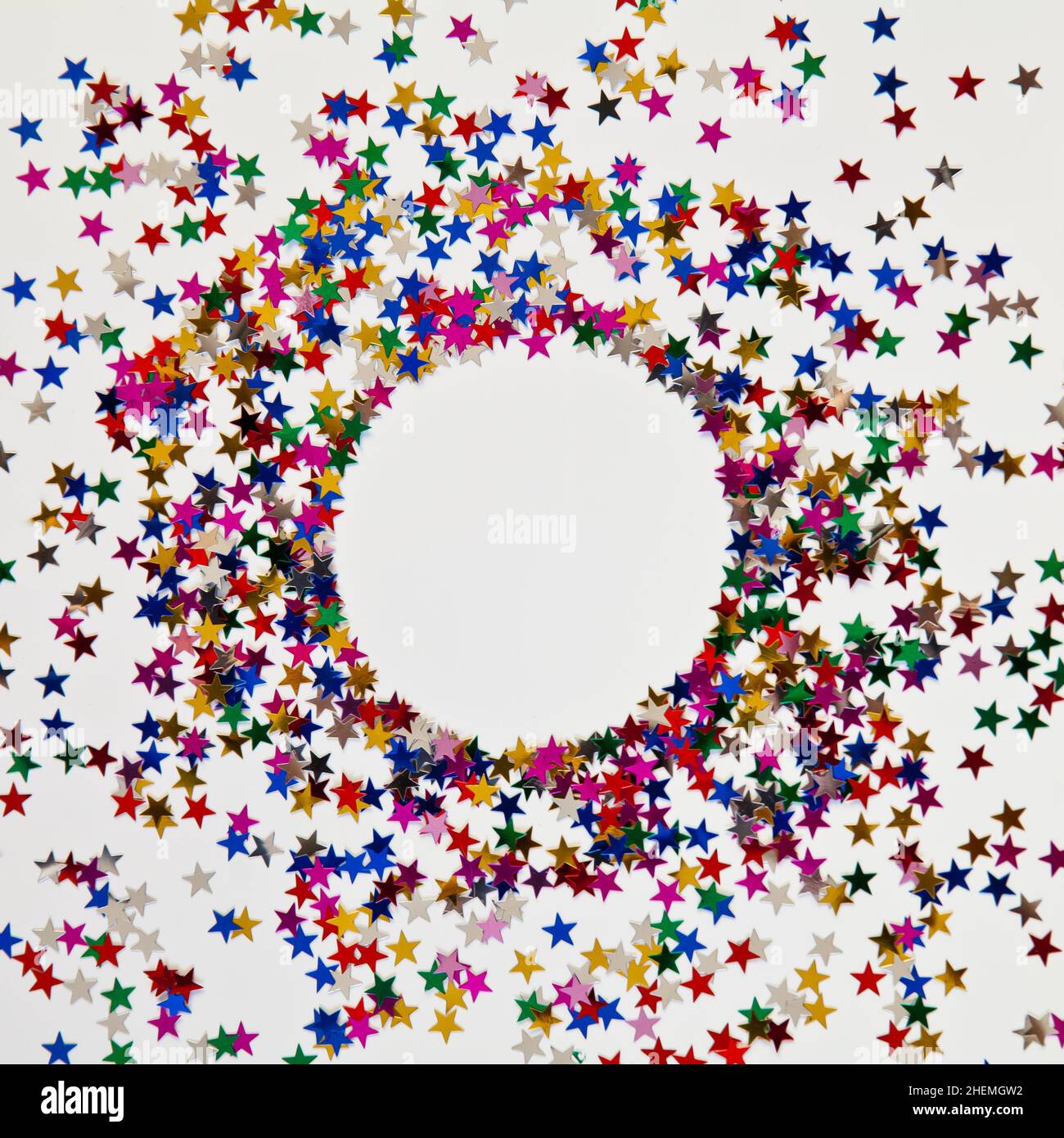 Kreisrahmen aus Glitzer auf weißem Hintergrund mit Copyspace. Modell. Mehrfarbige Sterne. Stockfoto