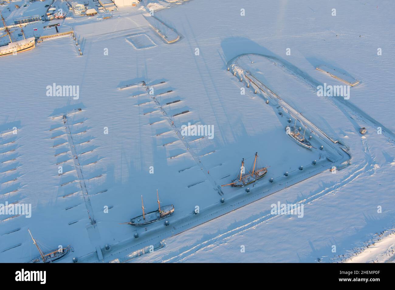 Ein leerer neuer Hafen und mehrere alte Fregatten unter dem Schnee an einem frostigen Winterabend Stockfoto