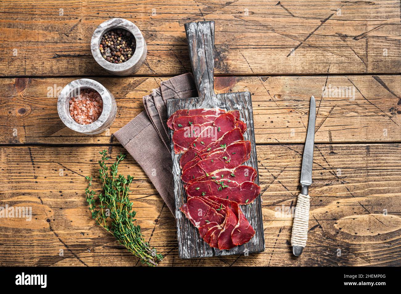 Getrocknete Pastrami-Scheiben, Rinderfleisch mit Kräutern auf Holzbrett. Holzhintergrund. Draufsicht Stockfoto