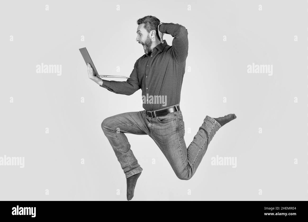 Überrascht energischer Mann springen während der Arbeit online auf Laptop Beeilen Sie sich zum Einkaufen, Überraschung. Stockfoto