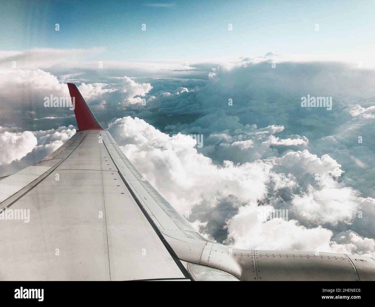 Blick auf den Himmel von oben auf die Wolken und den Flugzeugflügel. Aufgenommen aus dem Flugzeugfenster. Stockfoto