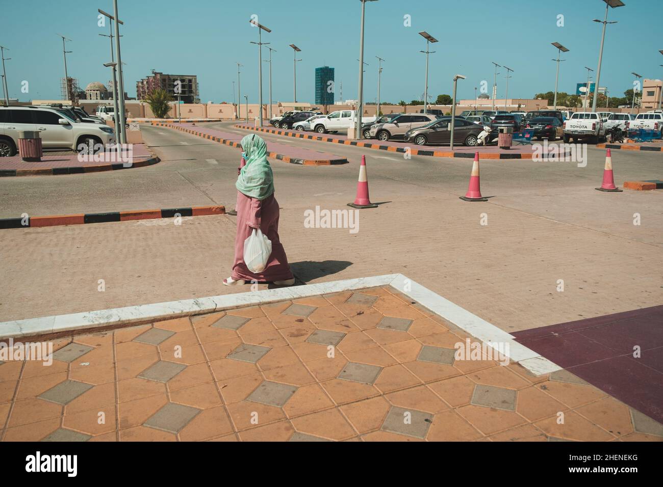 Dschibuti, Dschibuti - 17. Mai 2021: Eine Frau mit grünem Schal läuft auf dem Parkplatz eines Einkaufszentrums in Dschibuti. Redaktionelle Aufnahme in Dschibuti. Stockfoto