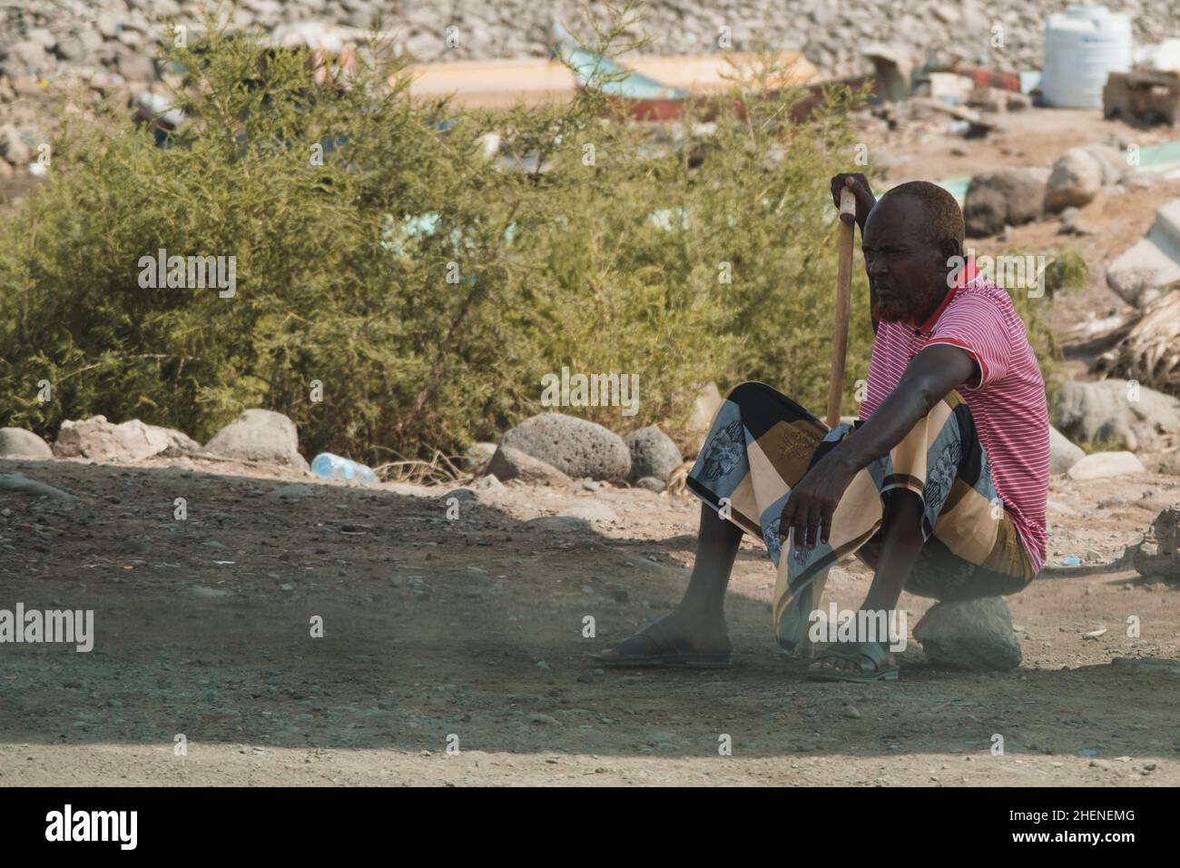 Dschibuti, Dschibuti - 21. Mai 2021: Ein Mann aus Dschibuti sitzt auf einem Stein. Redaktionelle Aufnahme in Dschibuti. Stockfoto