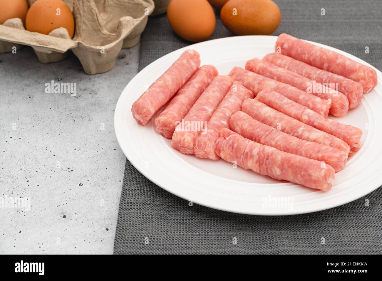Rohe Hähnchenfrühstückswürste aus nächster Nähe auf weißem Teller Stockfoto