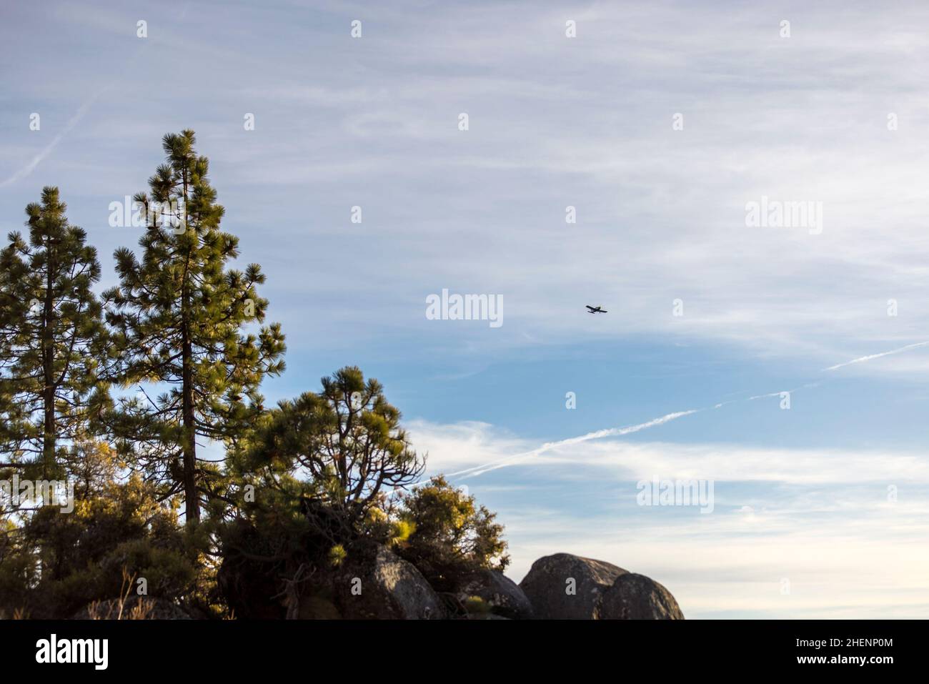 Ein kleines Flugzeug fliegt hoch über einem Lake Tahoe Strand Stockfoto