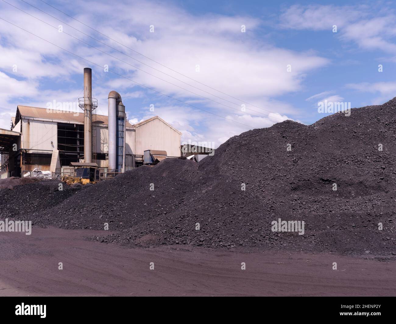 Haufen Kohle, die zur Dampfproduktion mit Kesseln in Industrieanlagen verwendet werden. Rauchschwaden des Kessels im Hintergrund. Stockfoto