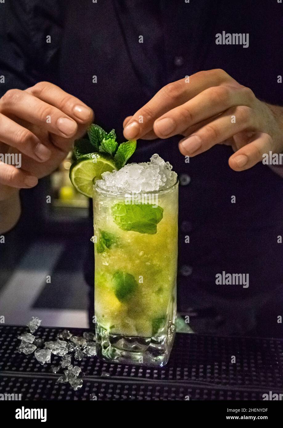 Ein alkoholischer Mojito-Cocktail, der von einem Barkeeper in einer Bar den letzten Schliff erhält Stockfoto