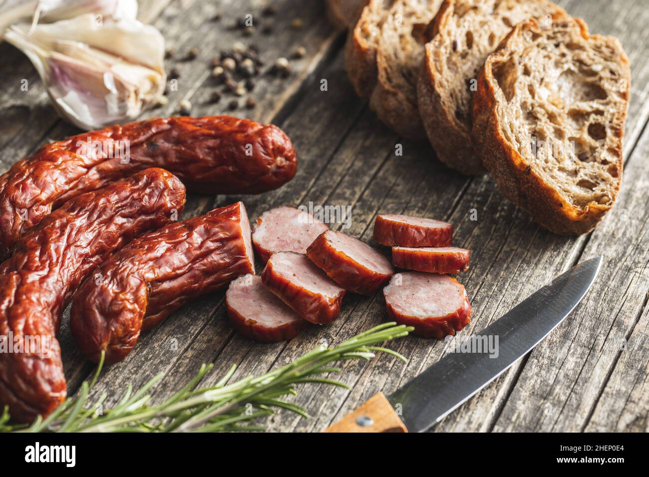 Geräucherte Schweinswürste. Geschnittene Salami auf Holztisch. Stockfoto