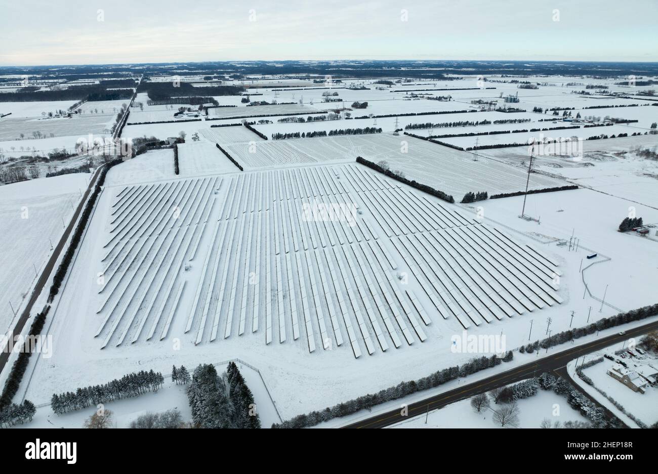 Schneebedeckte Sonnenkollektoren auf einer Solarfarm werden am Morgen eines Wintertages in der ländlichen kanadischen Gemeinde gesehen. Stockfoto