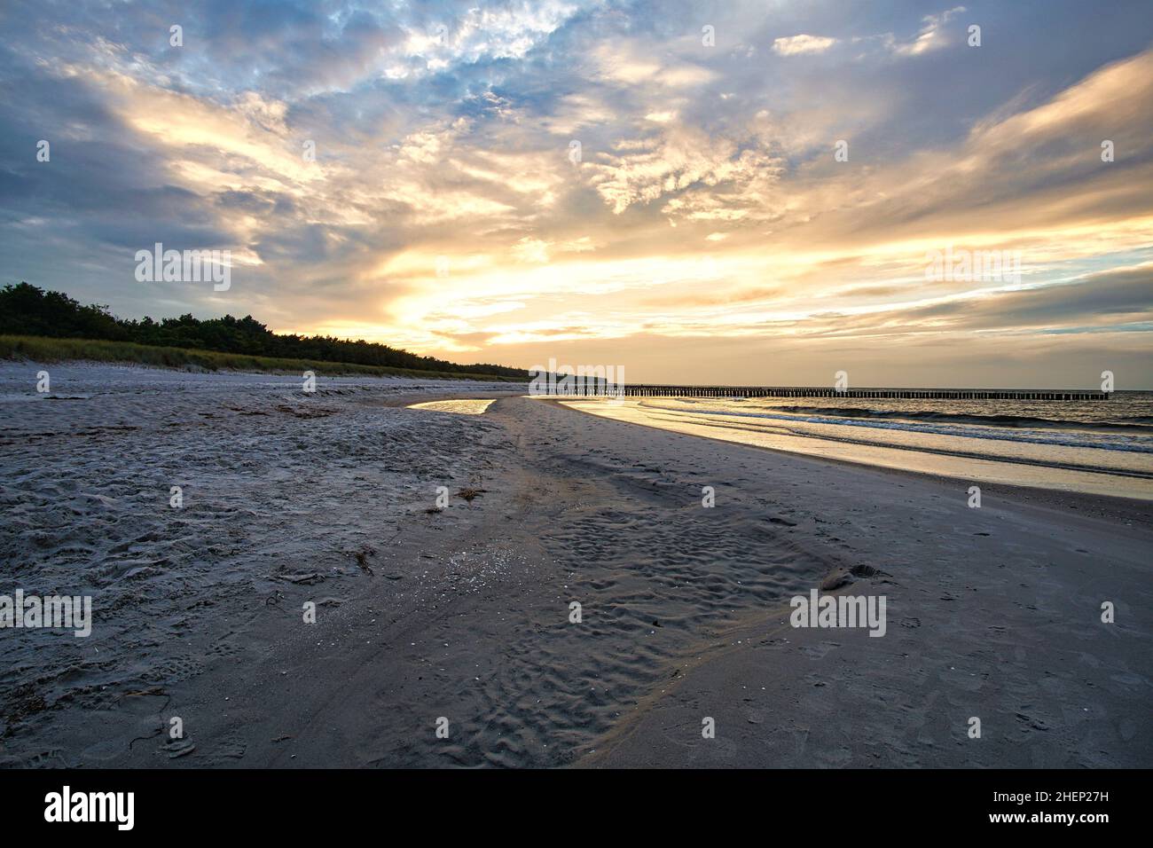 Sonnenuntergang an der ostseeküste mit Wolken am Himmel und Spiegelungen im Wasser. Dazu das Rauschen des Meeres und eine frische Brise um die Nase. Stockfoto
