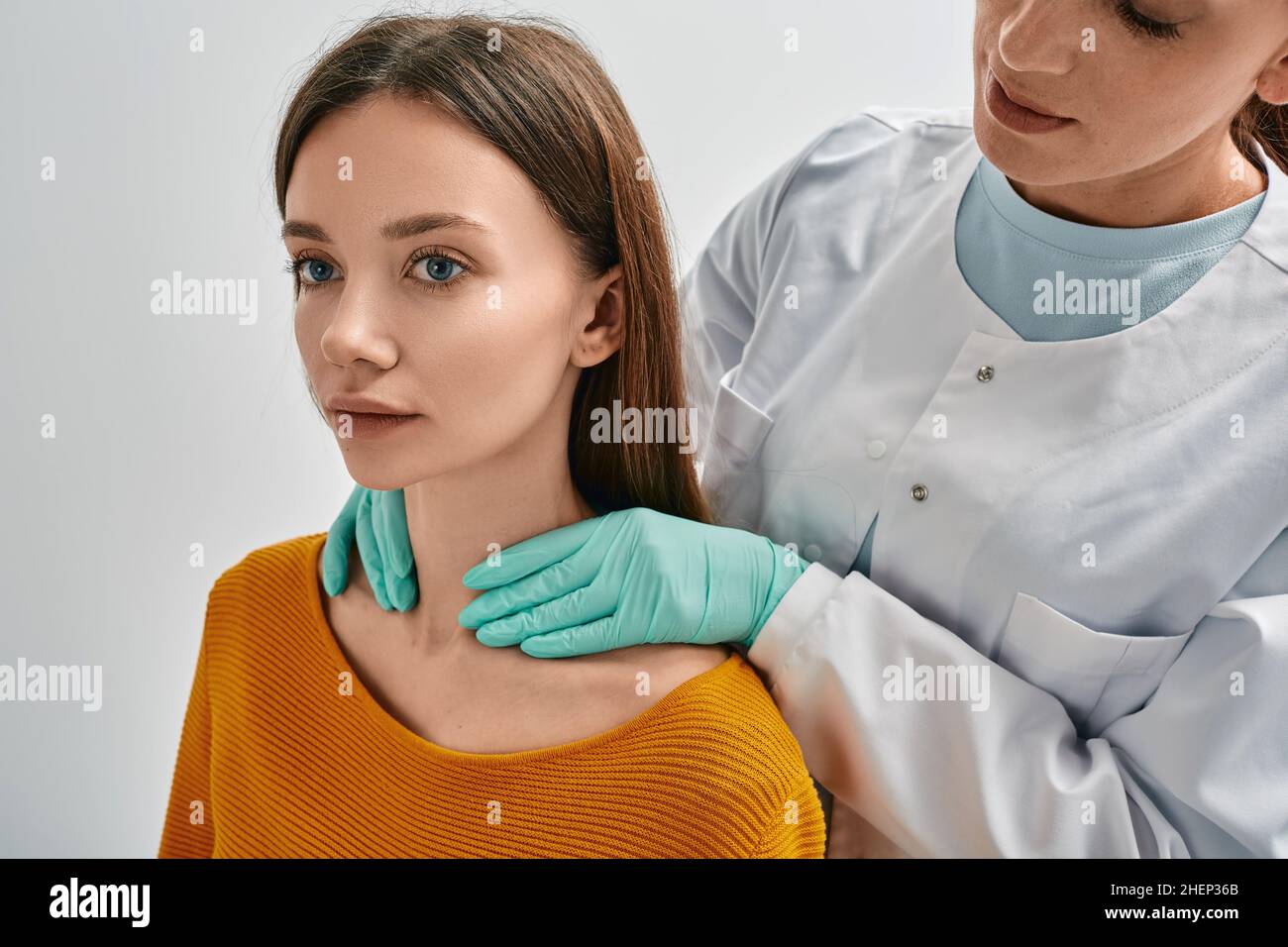 Endokrinologe, der die Schilddrüse eines erwachsenen weiblichen Patienten durch Palpation überprüft. Frau hat eine vergrößerte Schilddrüse und Hormone sind nicht normal Stockfoto