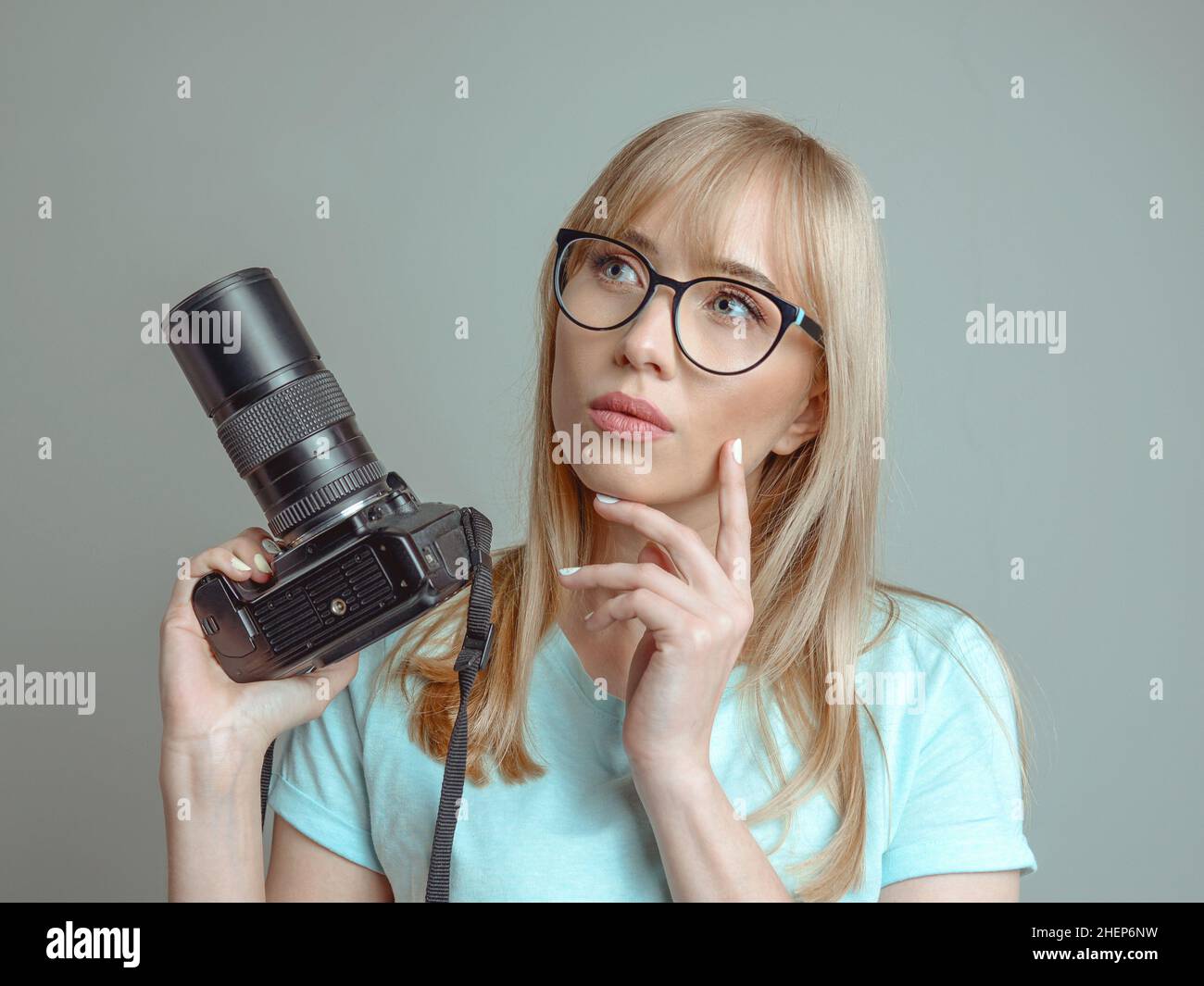 Blonde stilvolle fröhliche Frau Fotograf in Brille und halten Fotokamera. Hobby, Arbeit, Drehkonzept Stockfoto