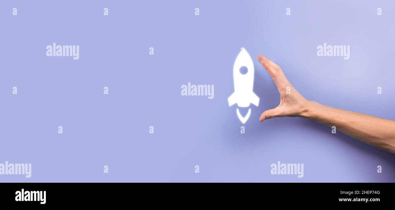 Männliche Hand hält Rakete Symbol, das startet, starten auf blauem Hintergrund. Rakete startet und fliegt aus, Business Start up, Symbol-Marketing auf Modus Stockfoto