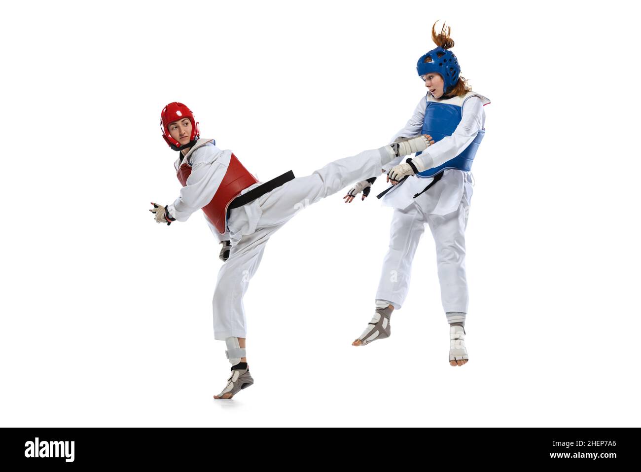 Dynamisches Porträt von zwei jungen Frauen, Taekwondo-Praktizierenden, die isoliert auf weißem Hintergrund zusammen trainieren. Konzept des Sports, Fähigkeiten Stockfoto