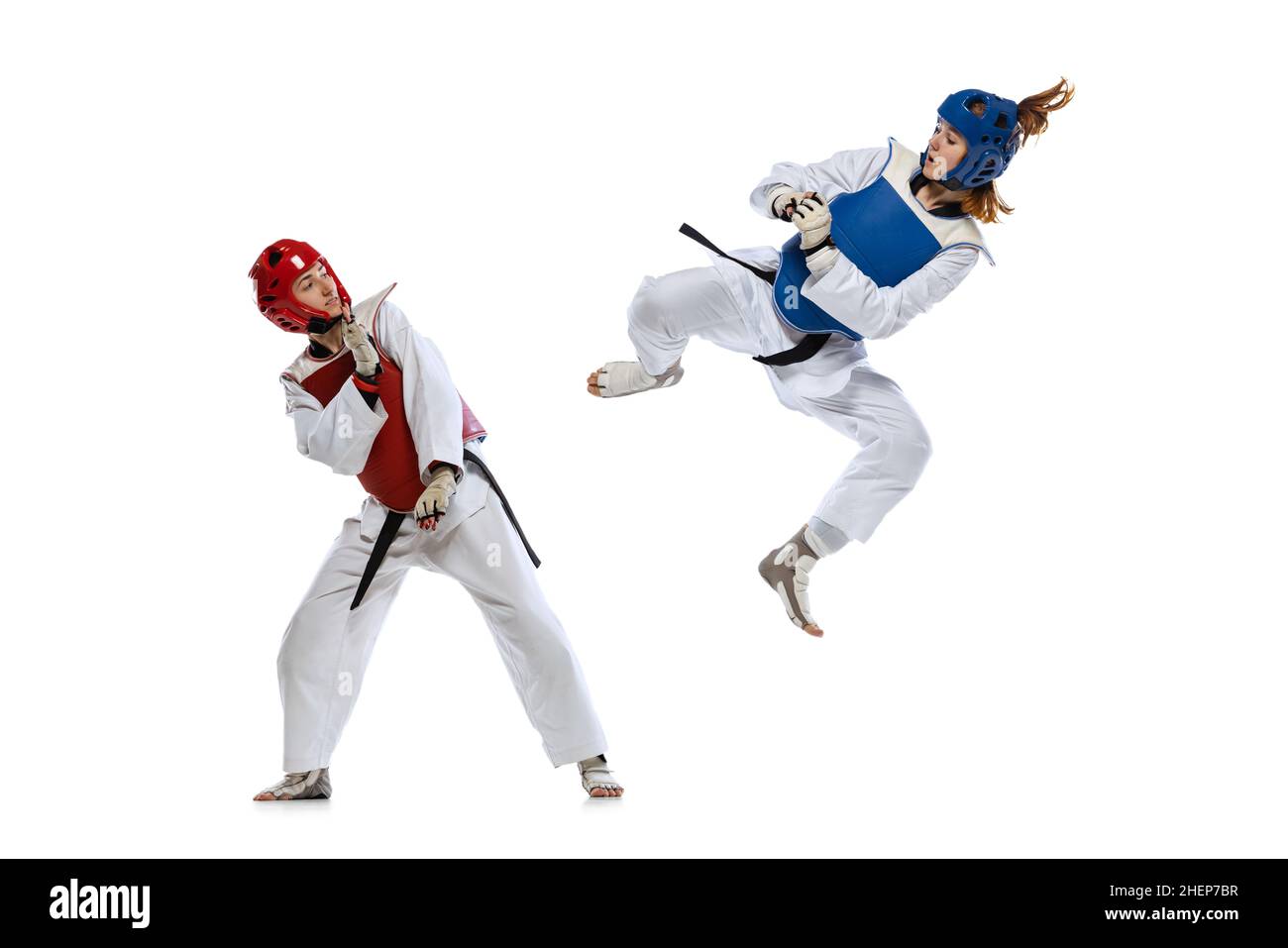 Dynamisches Porträt von zwei jungen Frauen, Taekwondo-Praktizierenden, die isoliert auf weißem Hintergrund zusammen trainieren. Konzept des Sports, Fähigkeiten Stockfoto
