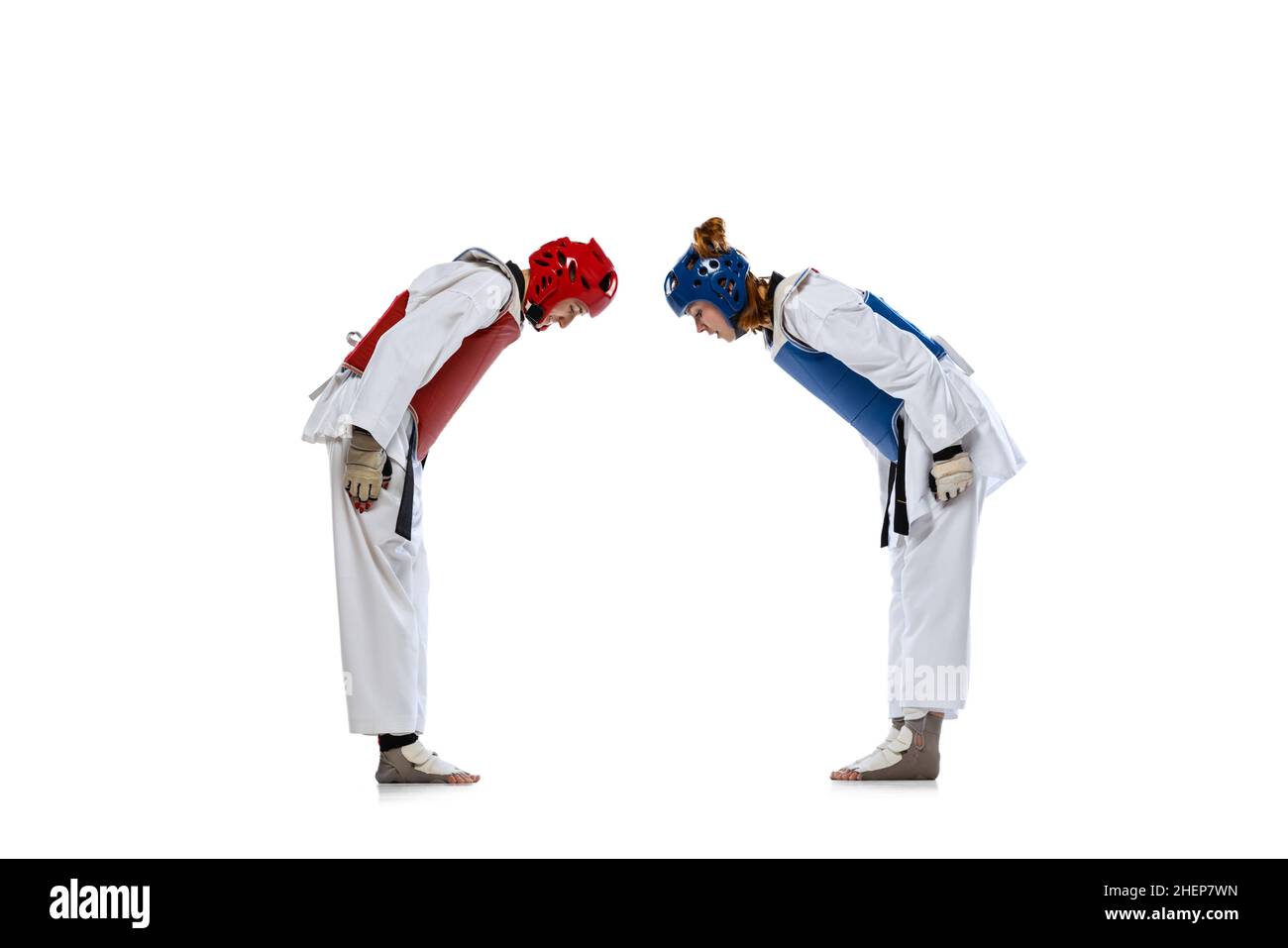 Studioaufnahme von zwei jungen Frauen, Taekwondo-Athleten begrüßen sich isoliert auf dunklem Hintergrund. Konzept des Sports, Fähigkeiten Stockfoto
