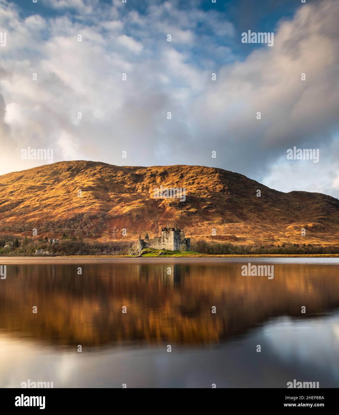 Kilchurn Castle, Loch Awe, Argyll & Bute, Schottland. Warme Sonnenuntergangsfarben, die die Berge und das Schloss erleuchten, mit dramatischen Sturmwolken am Himmel. Stockfoto