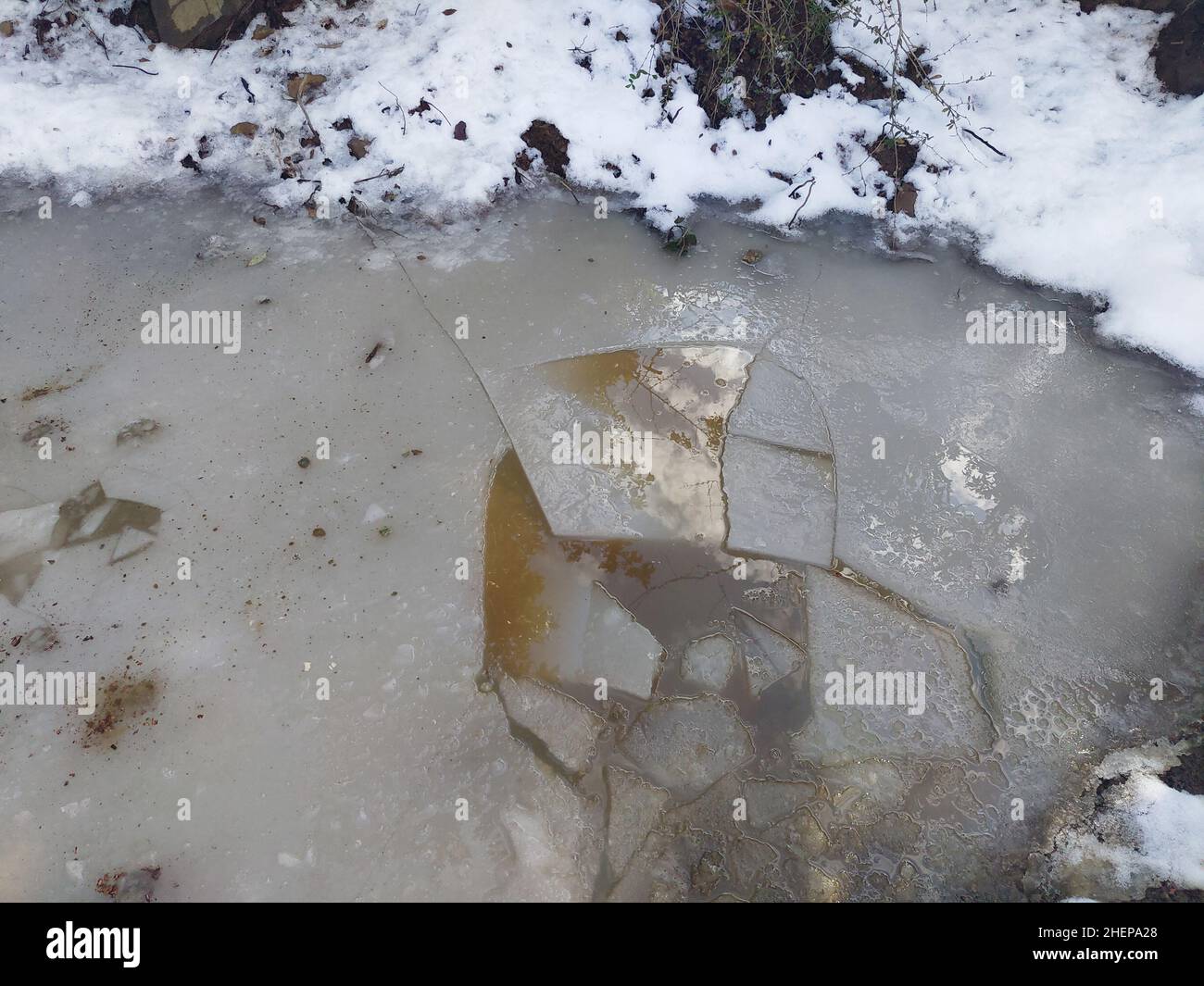 Eine Nahaufnahme einer gefrorenen Wasserpfütze mit Schnee im Winter. Stockfoto