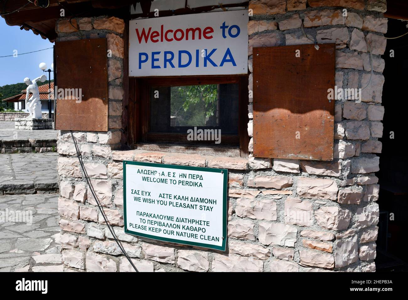 Perdika, Griechenland - 29. Juni 2021: Kiosk mit Willkommenstafel und Skulptur eines Diskuswerfers auf dem Hauptplatz im Bergdorf in Epirus Stockfoto