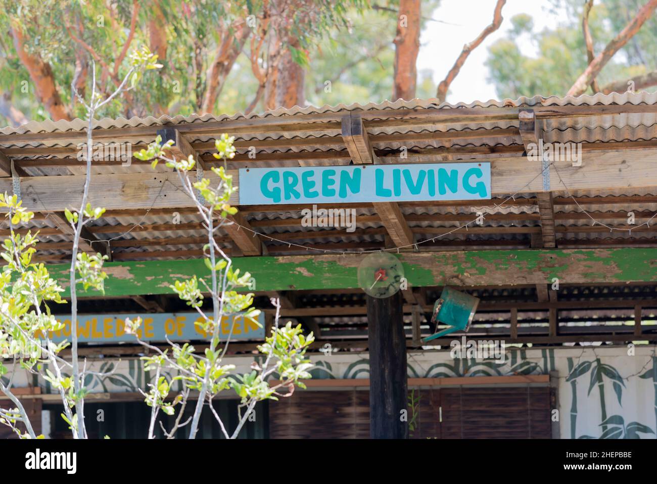 Ein Schild mit der Aufschrift Green Living über einem offenen Schuppen mit verzinktem Dach und Eukalyptusbäumen im Hintergrund, in Australien Stockfoto