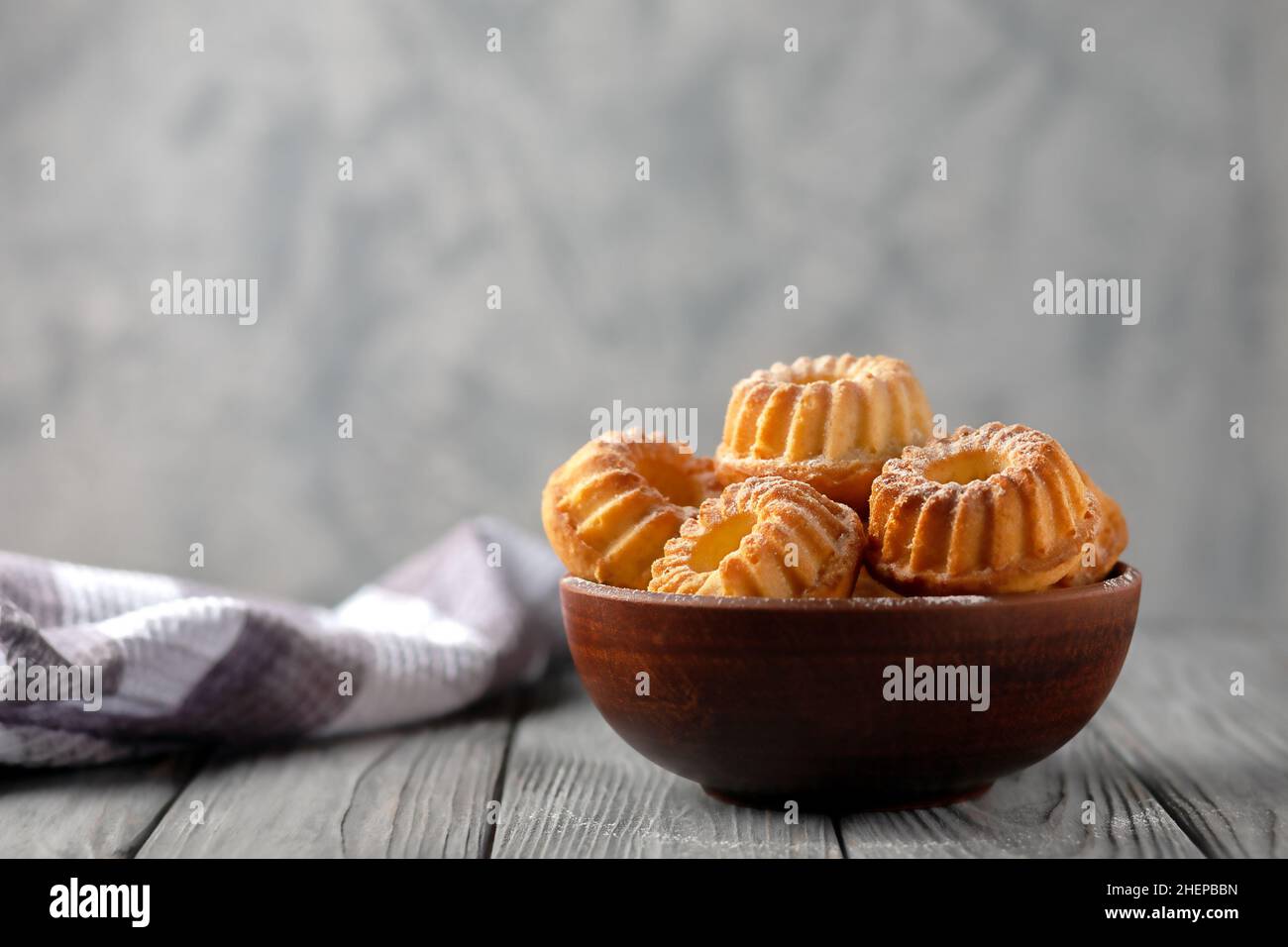 Frisch gebackene hausgemachte Muffins in einer Keramikschale auf Holzboden Stockfoto