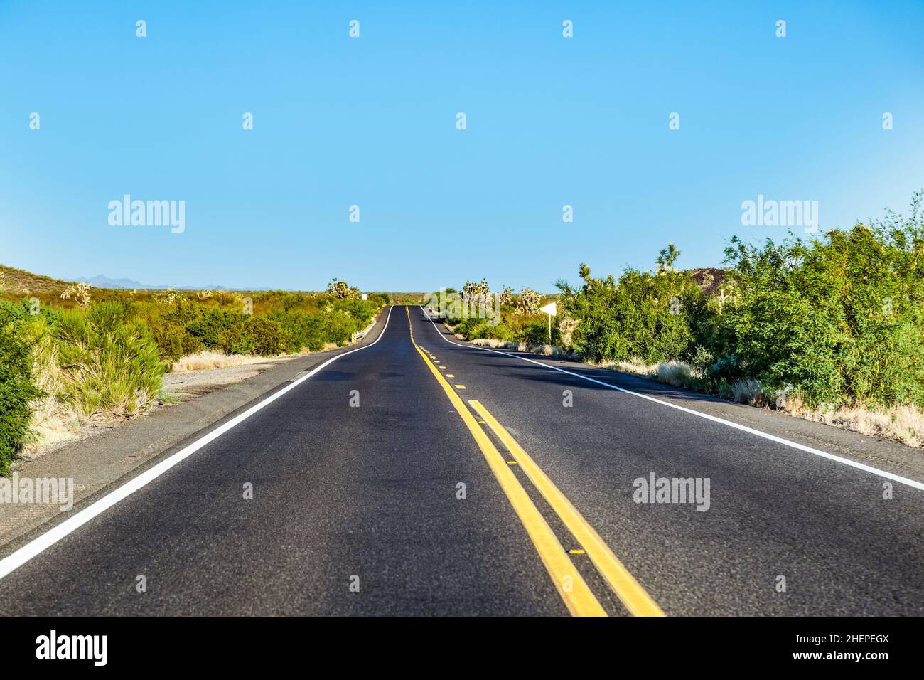 Leere Straße mit gelbem Streifen bei schönem Sonnenuntergang Stockfoto