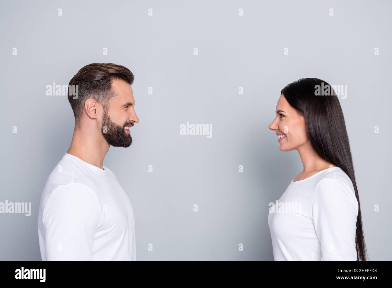 Foto von niedlichen süßen Schwester Bruder tragen weiße Hemden lächelnd suchen einander isoliert grauen Hintergrund Stockfoto