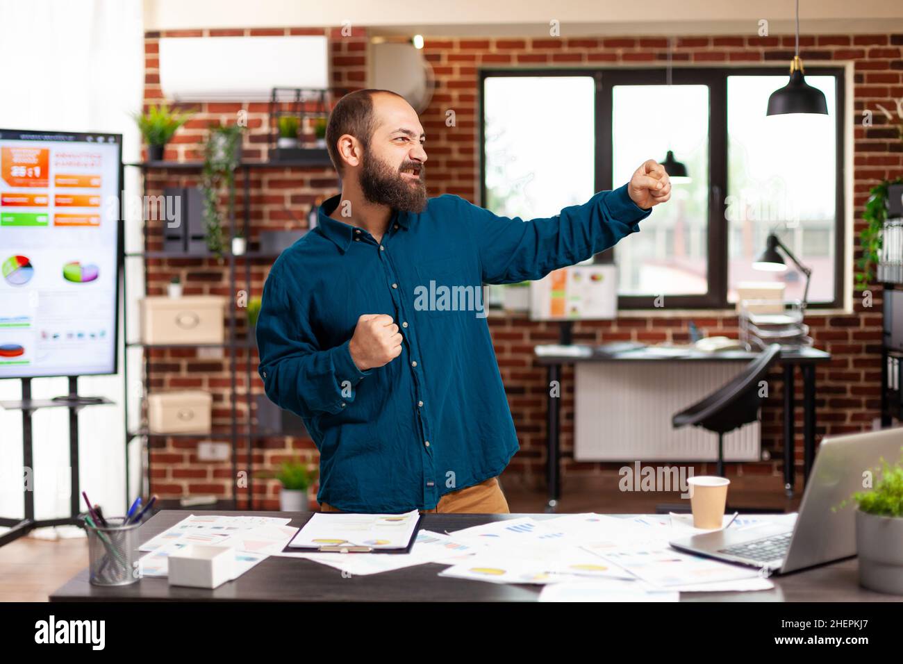 Glücklicher ehrgeiziger selbstbewusster Unternehmer, der nach erfolgreicher Marketingpartnerschaft Triumph im Startup-Büro tanzt. Geschäftsmann Mann gewinnen Geschäftspartnerschaft machen guten Gewinn Stockfoto
