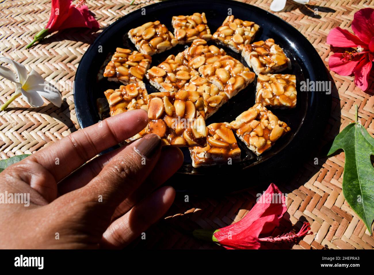 Person, die das Servieren hält Essen Erdnussbonbons traditionelle indische Süßigkeiten Erdnusschikki, serviert und gegessen während des Makarsankranti-Festivals.hergestellt aus Erdnuss Stockfoto